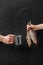 Male and female hands holding metal mug and salted dried roach