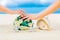 Male and female hands, two wedding rings with two starfish, wedding bouquet and a large shell on a sandy tropical beach. Blue sea