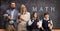 Male and female math teachers with a schoolgirl and scholboy in front of a blackboard