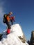 Male and female mountain climber on an exposed rocky summit ridge on their way to a high alpine mountain peak