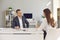 Male and female office workers sitting at a desk and discussing office workflows.