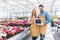 Male and female owners of glasshouse holding Open board