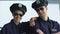 Male and female police officers in sunglasses smiling into camera, city patrol