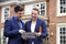 Male And Female Realtor Standing Outside Residential Property