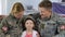 Male and female soldiers hugging daughter in military cap, smiling on camera