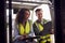 Male And Female Staff Operating Fork Lift Truck In Modern Warehouse