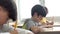 Male and female students sitting at desk in classroom writing in notebook. Boy and girl in elementary age