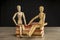 Male and female wooden mannequins sitting on books