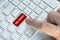 A male finger presses a color button on a gray silver keyboard of a modern laptop. Button with inscription close up