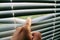 Male finger pushes white horizontal aluminum blinds