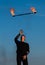 Male fire performer manipulate with flaming baton on blue sky outdoors, man