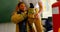 Male firefighter  helping African American girl to wear fire uniform in classroom. Schoolgirl smilin