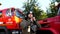 Male firefighter putting a helmet against background of a fire engine. Young fireman in full equipment near a big red