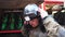 Male firefighter taking off helmet against background of a red truck. Young fireman removing equipment from himself