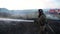 Male firefighter in uniform extinguishes burning dry grass using fire hose at countryside. Professional fireman in full