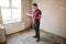 Male First Time Buyer Looking At House Survey In Room To Be Renovated