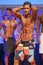 Male fitness model shows his physique in swimsuit om stage