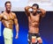 Male fitness model shows his physique in swimsuit om stage