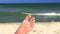 Male foot on sand beach and sea waves