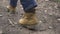 Male foot in shoes walking on countryside road back view. Man in shoes from beige leather walking on footpath, low angle