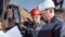 Male foreman and worker in helmet and glasses discussing construction plan looking on drawing