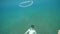 A male free diver underwater and a bubble ring ascending in slow motion.