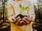 Male free-spirited teen holding green plant in soil relaxing in luscious woodlands