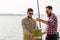 Male friends with fish and fishing rods on pier