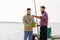 Male friends with fish and fishing rods on pier