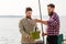 Male friends with fish and fishing rods on pier