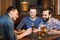 Male friends with smartphones drinking beer at bar