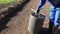 Male gardener filling soil earth roller with water from hose. Static shot