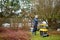 Male gardener using electric garden grinder to shred cut tree branches during spring cleaning. Cleanup around the house. Spring