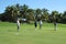 Male golf player making his putt with foursome