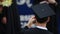 Male graduate in academic dress taking photo of friends receiving diplomas