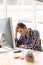 Male graphic designer with hand on head sitting at desk in a modern office