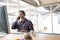 Male graphic designer talking on mobile phone at desk in a modern office