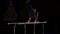 Male gymnast acrobat performs handstand on parallel bars in a dark room in slow motion