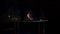 Male gymnast acrobat performs handstand on parallel bars in a dark room in slow motion