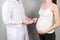 Male gynecologist giving pills to pregnant woman during appointment at colored background. Visit To A Doctor Pregnancy Healthcare