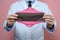 Male gynecologist holding reusale menstrual pads on pink wall.