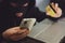 Male hacker in a robber mask uses phone, credit card and laptop in some fraudulent scheme. Cyber thief stole the personal data and