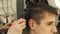 Male hairdresser cutting hair with haircut trimmer in barbershop close up. Haircutter doing men haircut with electric