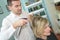 Male hairdresser making haircut for female customer