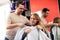 Male hairdresser puts coat to blonde client at beauty salon