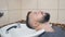 Male in hairdressing saloon, close shot. Man puts his head on white washstand to shampoo hair. Interior of barbershop