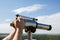 Male hand adjusts sharpness on a touristic binocular against forest panorama