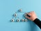 Male hand arranges company hierarchical organizational chart of wooden cubes on blue background