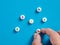 Male hand arranges medical pills with vitamin symbols on blue background