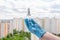 Male hand in blue medical glove holds antiseptic gel on cityscape